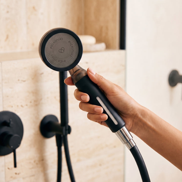 PICKI NIKI filtered shower head held in hand, sediment filter visible through the window in the handle